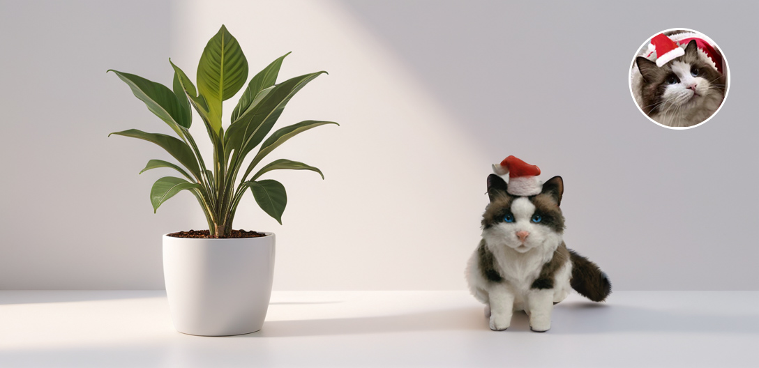 A realistic wool felt cat sculpture wearing a small Santa hat, positioned next to a potted green plant on a light-colored surface.