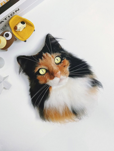 
A wool felt artwork depicting a realistic long-haired calico cat.